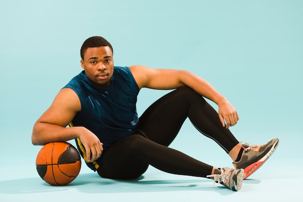 Vista lateral del hombre atlético posando con baloncesto