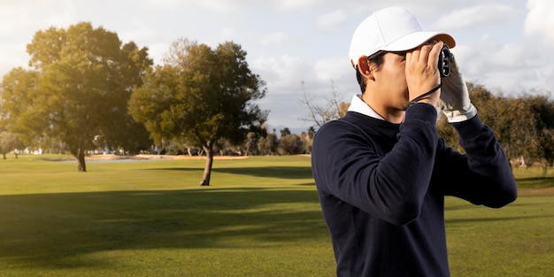 Vista lateral del hombre con binoculares en el campo de golf