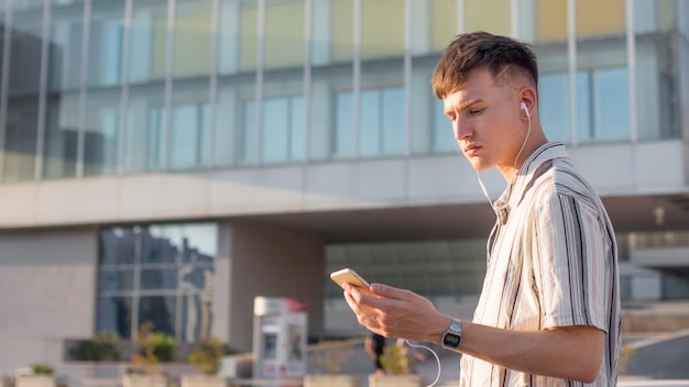 Vista lateral del hombre en la ciudad escuchando música con auriculares