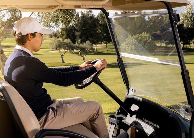 Vista lateral del hombre conduciendo un carrito de golf