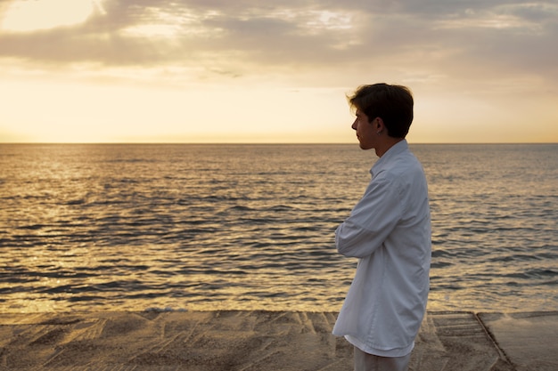 Vista lateral del hombre contemplativo en la playa.