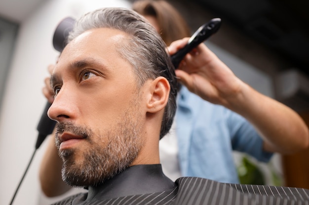 Foto gratuita vista lateral del hombre cortándose el pelo