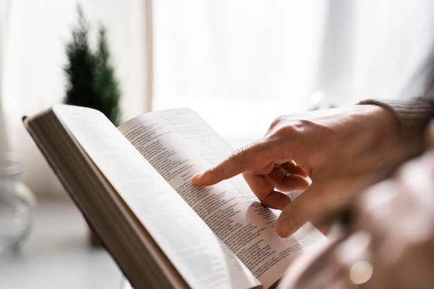 Vista lateral del hombre con el dedo para leer la Biblia