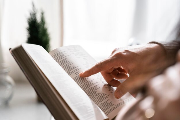 Vista lateral del hombre con el dedo para leer la Biblia