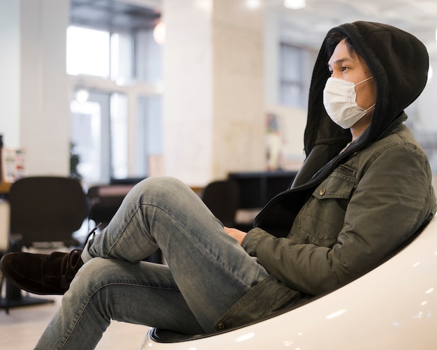 Vista lateral del hombre descansando mientras usa una máscara médica
