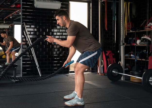 Vista lateral hombre entrenando en el gimnasio