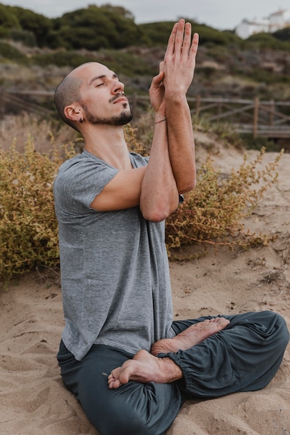 Vista lateral del hombre fuera meditando mientras hace yoga