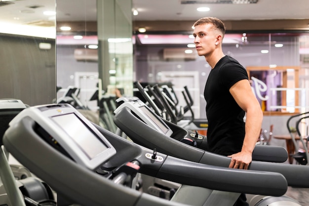 Vista lateral del hombre en el gimnasio en cinta rodante