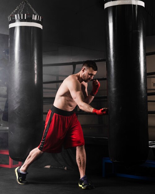 Vista lateral hombre con guantes de boxeo rojo