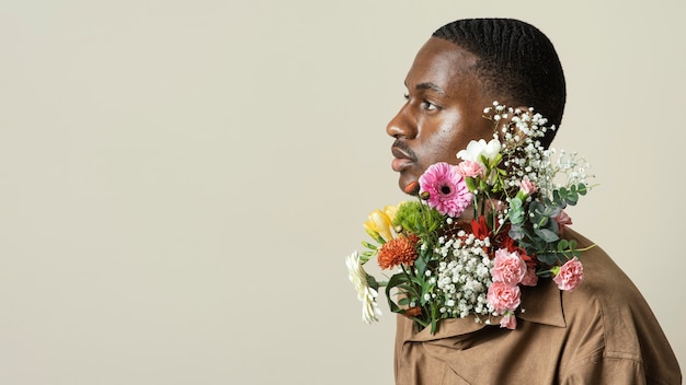 Vista lateral del hombre guapo posando con ramo de flores y espacio de copia