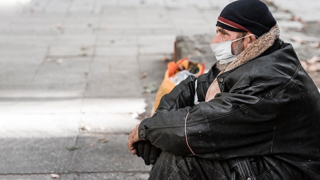 Vista lateral del hombre sin hogar al aire libre con bastón y espacio de copia