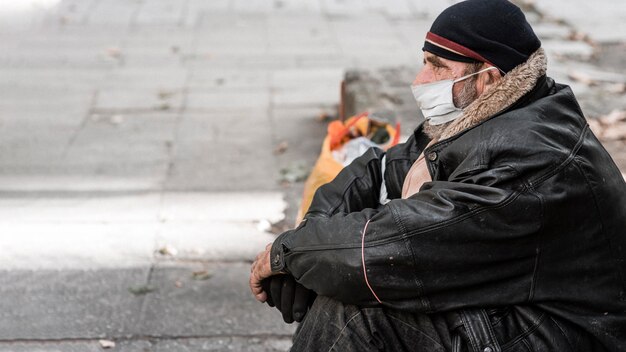 Vista lateral del hombre sin hogar al aire libre con bastón y espacio de copia