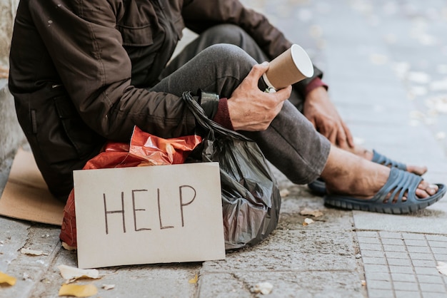 Vista lateral del hombre sin hogar con taza y signo de ayuda