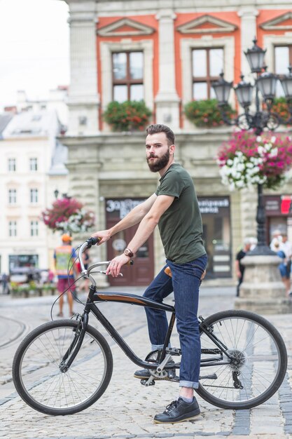 Vista lateral de un hombre joven con bicicleta en la ciudad