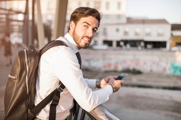 Vista lateral de un hombre joven que usa el teléfono móvil