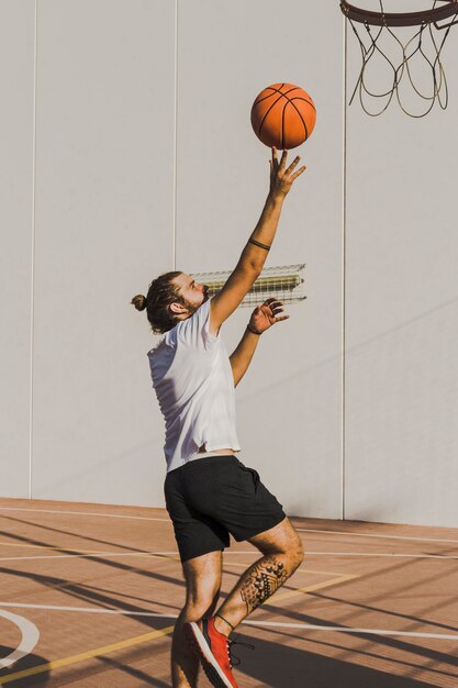 Vista lateral, de, un, hombre, lanzamiento, baloncesto, en, aro
