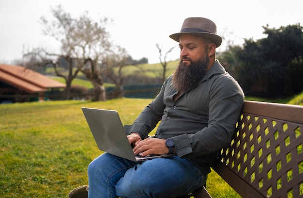 Vista lateral hombre con laptop al aire libre