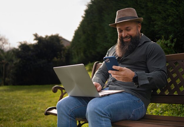 Vista lateral hombre con laptop al aire libre