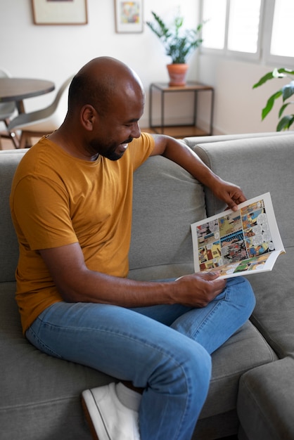Vista lateral hombre leyendo cómics en casa