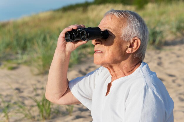 Vista lateral del hombre mayor con binoculares al aire libre