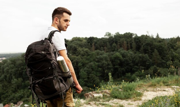 Vista lateral hombre con mochila en carretera