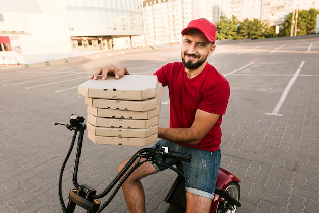 Foto gratuita vista lateral del hombre en motocicleta con cajas de pizza