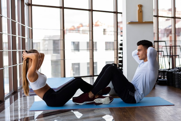 Vista lateral del hombre y la mujer haciendo abdominales