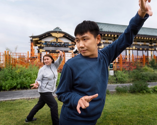 Foto gratuita vista lateral hombre y mujer practicando tai chi afuera