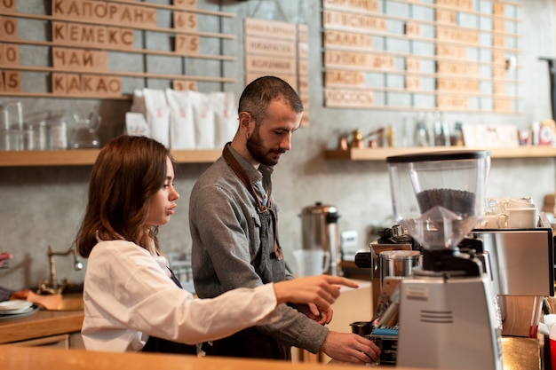 Vista lateral del hombre y la mujer que trabaja en la cafetería.