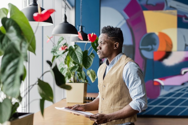 Foto gratuita vista lateral del hombre con papeles en el lugar de trabajo