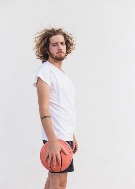 Foto gratuita vista lateral de un hombre con pie de baloncesto contra el fondo blanco