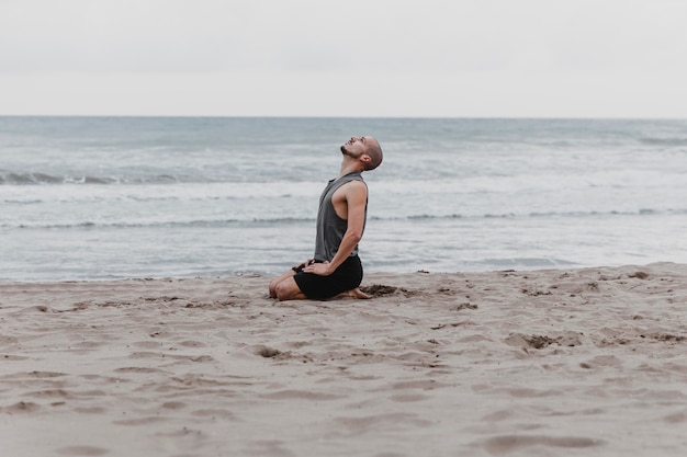 Vista lateral del hombre en la playa meditando