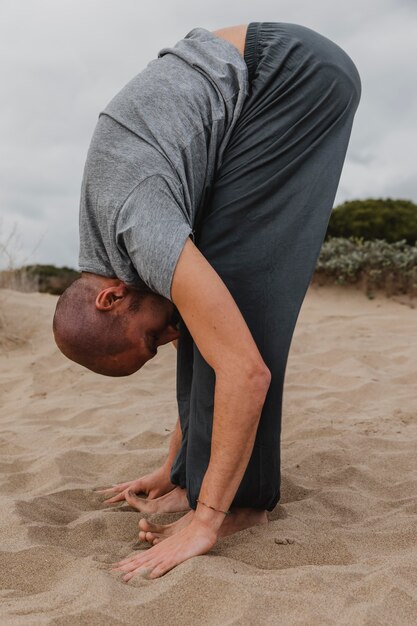 Vista lateral del hombre en posición de yoga al aire libre