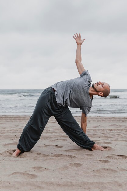 Vista lateral del hombre practicando posiciones de yoga fuera