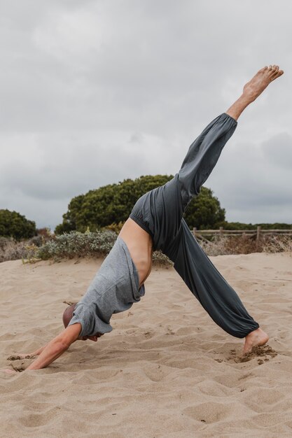 Vista lateral del hombre practicando yoga al aire libre