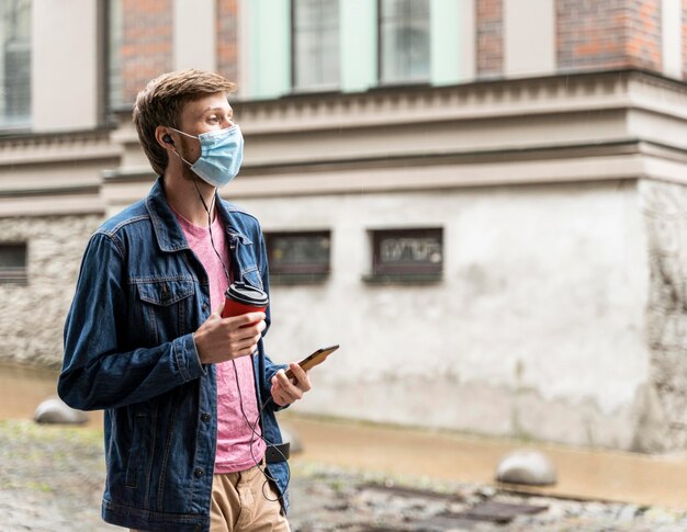 Vista lateral del hombre que llevaba una máscara médica exterior con espacio de copia