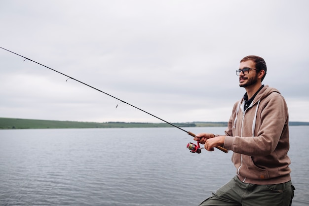 Vista lateral del hombre que pesca con la barra en el lago