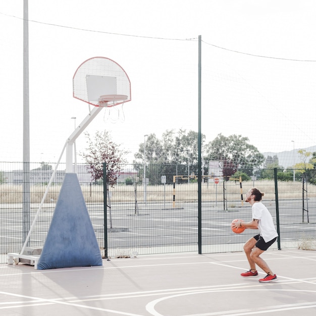 Vista lateral de un hombre que se prepara para lanzar el baloncesto en el aro