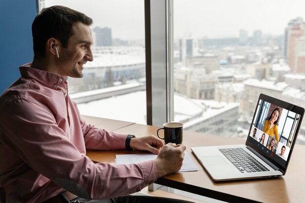 Vista lateral del hombre que tiene una videollamada en línea con compañeros de trabajo