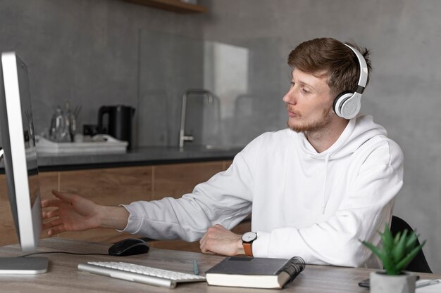 Vista lateral del hombre que trabaja en el campo de los medios con computadora y auriculares