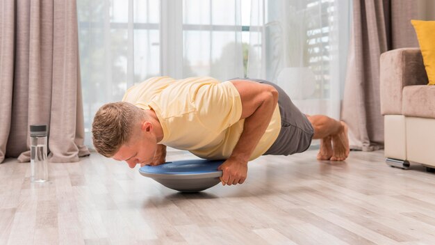 Vista lateral del hombre que trabaja en casa con bosu ball