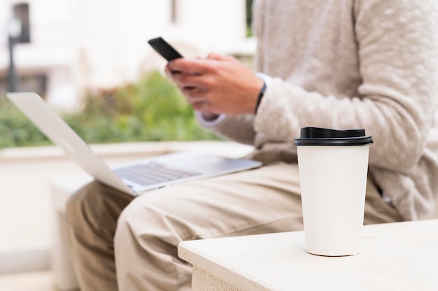 Foto gratuita vista lateral del hombre que trabaja en la computadora portátil mientras toma una taza de café