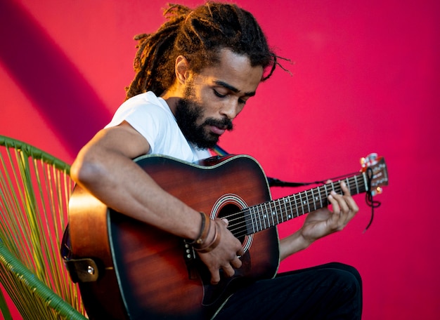 Foto gratuita vista lateral hombre con rastas tocando la guitarra