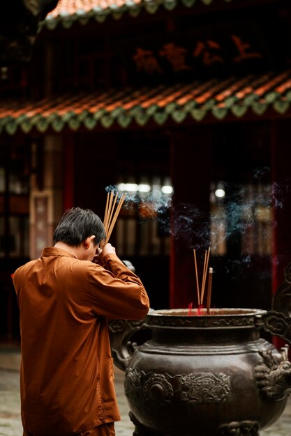 Foto gratuita vista lateral del hombre religioso en el templo con incienso ardiente y espacio de copia