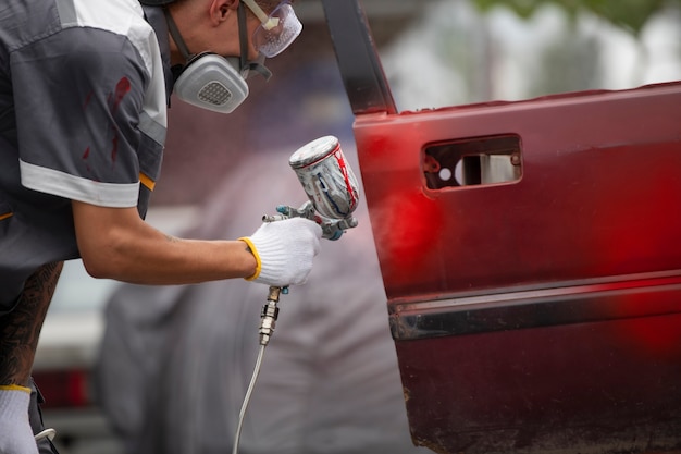 Foto gratuita vista lateral hombre rociando pintura en polvo en la puerta del coche
