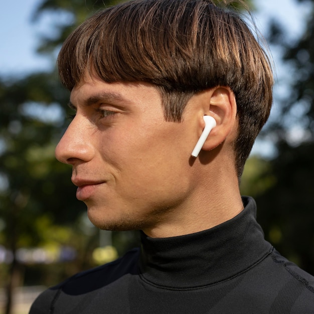 Vista lateral del hombre en ropa deportiva y auriculares al aire libre