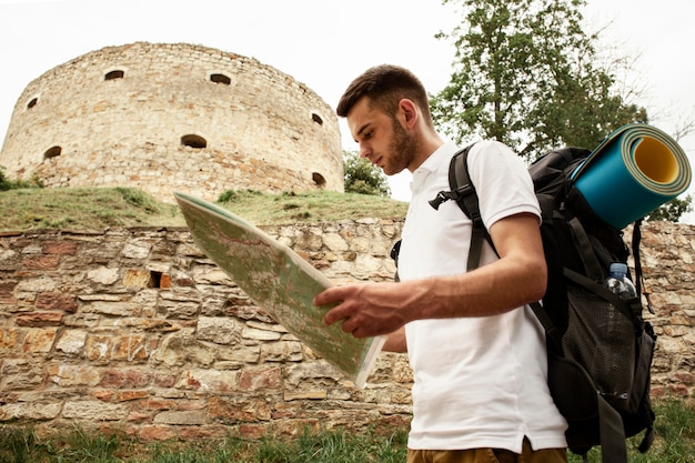 Foto gratuita vista lateral del hombre en las ruinas del castillo con mapa