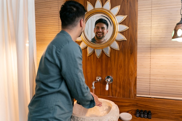 Vista lateral hombre sonriente mirando en el espejo
