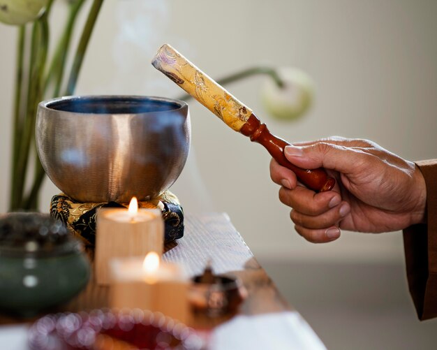 Vista lateral del hombre sujetando el objeto para la oración con velas y cuenco