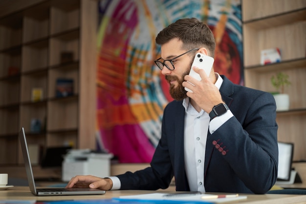 Vista lateral hombre con teléfono inteligente y computadora portátil